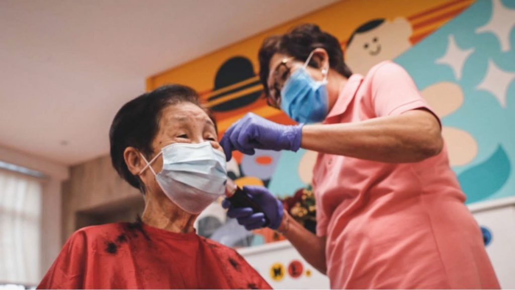 Mdm Cheok giving a haircut to a senior lady.