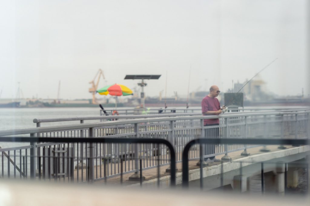 Lawrence Tai stands by the pier, line at the ready